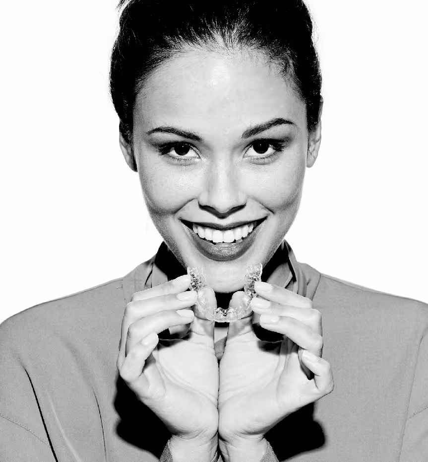 A Smilebar patient holding a clear Invisalign aligner before a fitting