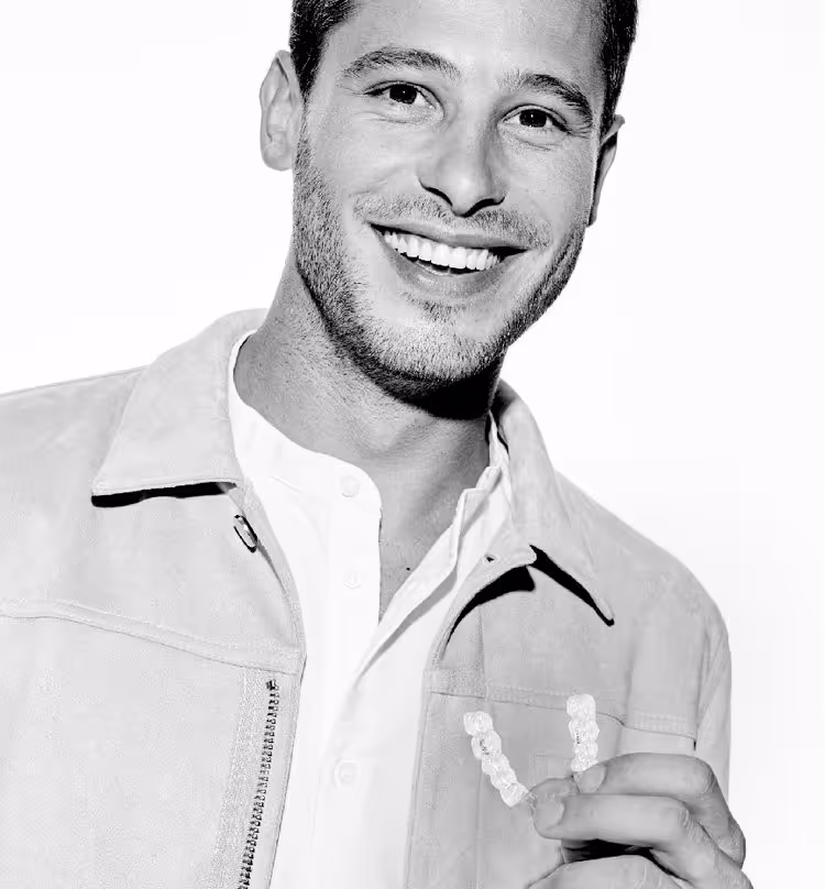 Smiling man holding clear Invisalign aligners