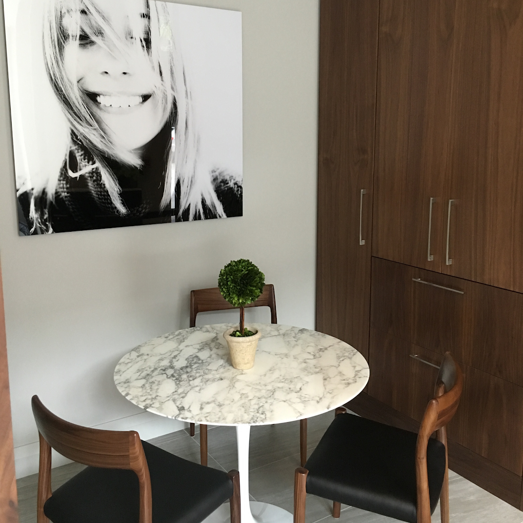 A black and white smile portrait above an arabescato marble pedestal table and walnut cabinetry