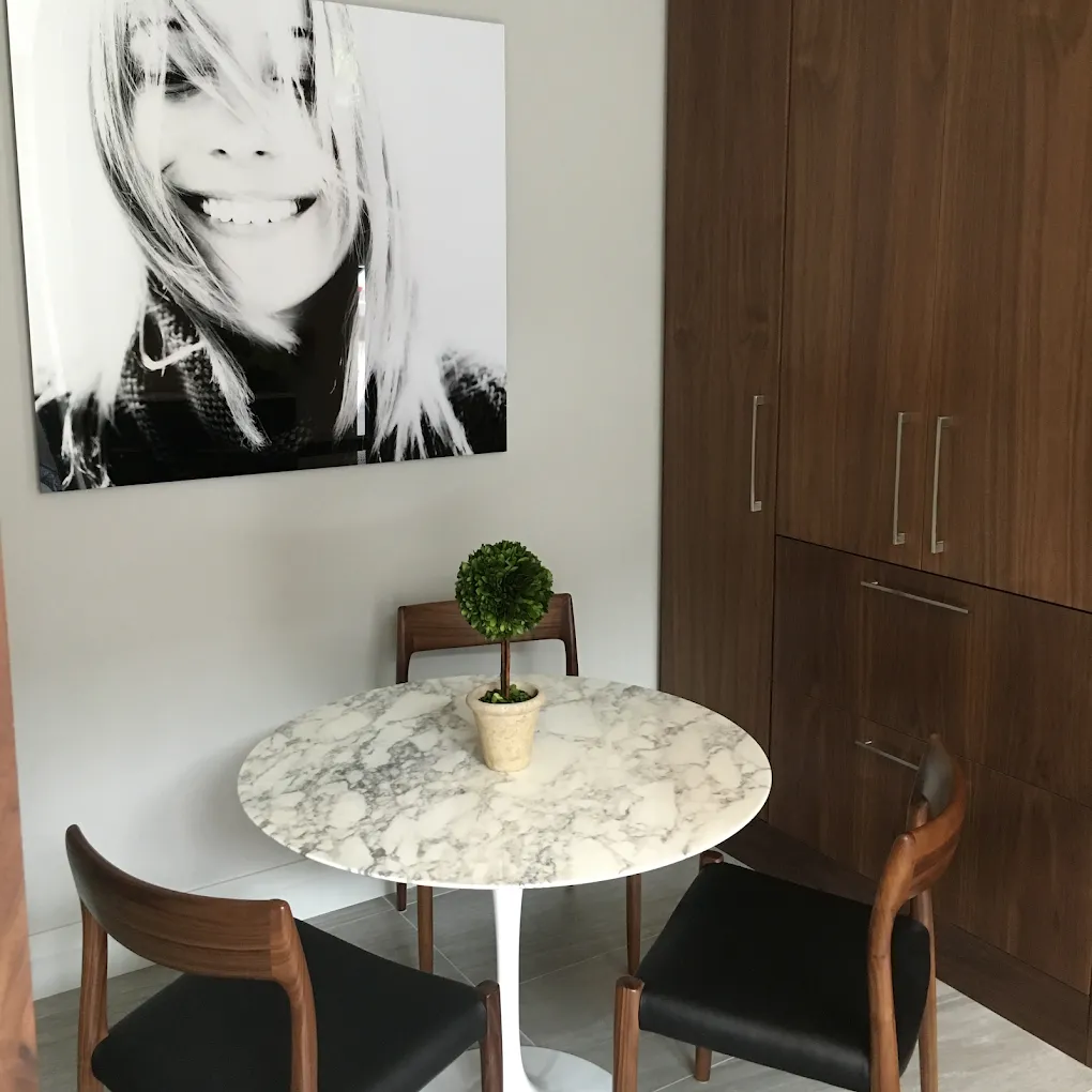 A black and white smile portrait above an arabescato marble pedestal table and walnut cabinetry